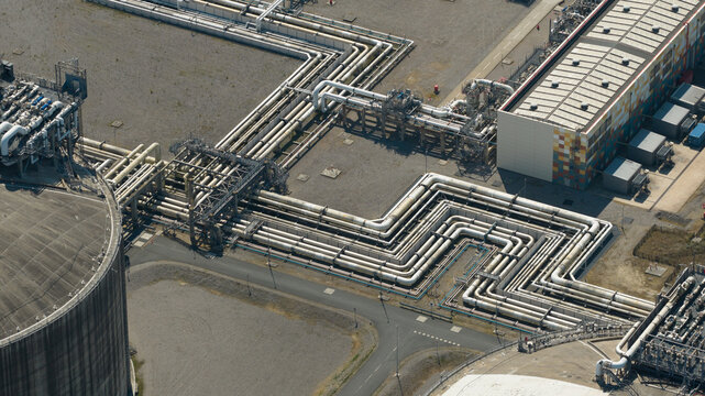 Aerial view of Dunkirk LNG Terminal featuring complex industrial piping networks, large storage tanks, and facility buildings in Loon-Plage, Hauts-de-France, France.