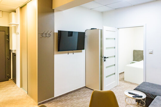 Modern hotel apartment interior with wall-mounted TV and open door to bedroom