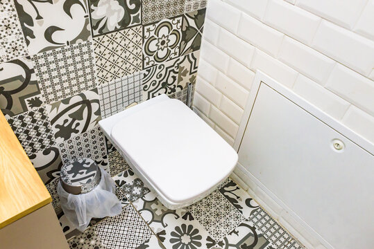 Modern wall-mounted toilet with geometric and patterned tiles in a stylish restroom