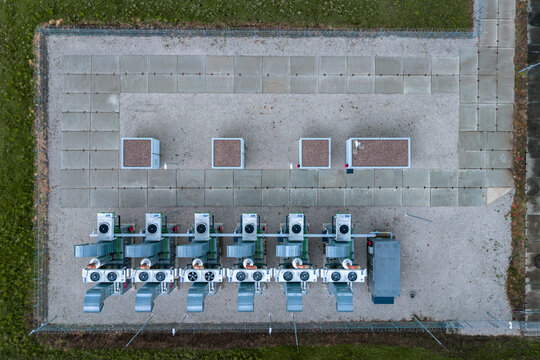Aerial view of a technical industrial installation featuring a row of compressor units on a gravel surface with concrete slabs in Nasedlovice, South Moravian Region, Czechia.