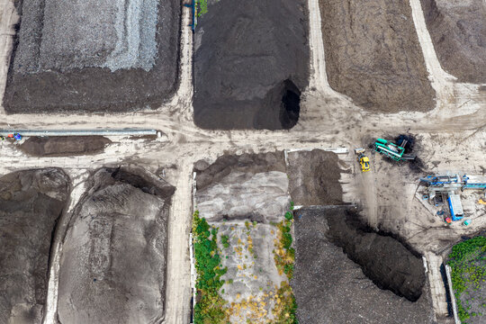 Aerial view of a compost processing facility with large piles of organic waste and heavy machinery, Netherlands.