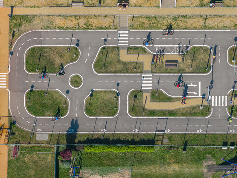 Aerial view of a children's traffic playground with people cycling on paved paths featuring road markings and crosswalks in Kyjov, South Moravian Region, Czechia.