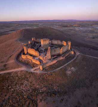 Aerial view of the historic ruins of Castle Almonacid of Toledo perched on a hill during the golden hour in Almonacid de Toledo, Castilla-La Mancha, Spain.