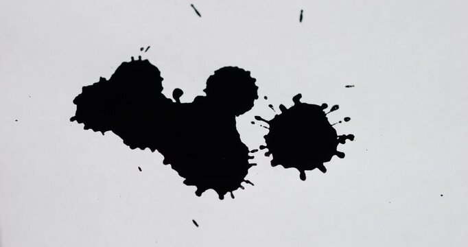 Ink splashes on a white sheet of paper. Black paint stains on a white background.
