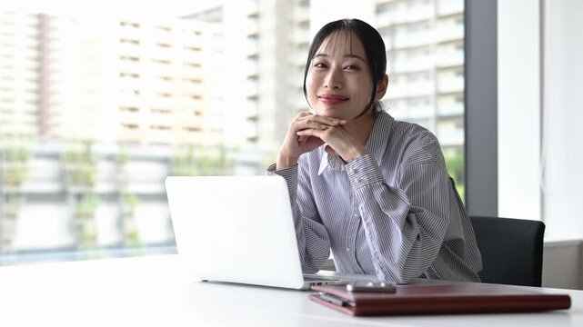 窓際でノートパソコンを使って仕事をする30代の日本人ビジネスパーソンの女性