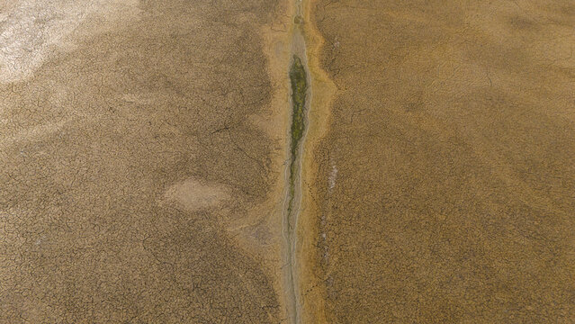 Aerial view of the dried-up lake bed of Cavuscugol with cracked earth patterns and a narrow central water channel in Cavuscugol, Konya, Turkey.