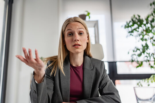Confident office professional expressing uncertainty with an open-hand gesture during a business discussion, symbolizing decision making, workplace challenges, collaboration, and leadership