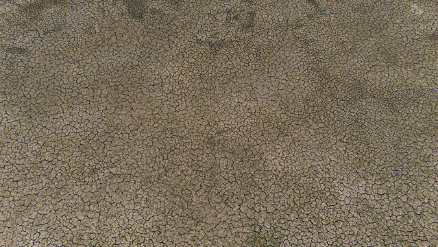 Aerial view of the dry, cracked lake bed of Cavuscugol showing parched soil and sparse vegetation in Cavuscugol, Konya, Turkiye.