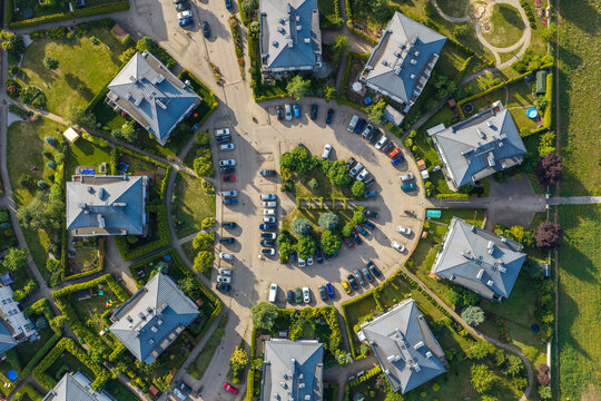 View of a residential cul-de-sac with modern houses, parked cars, and manicured green lawns in Pruszkow, Masovian Voivodeship, Poland.