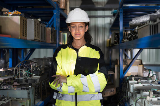 Portrait of woman worker using digital tablet working  and inspecting at shelves of electronic equipment parts in warehouse