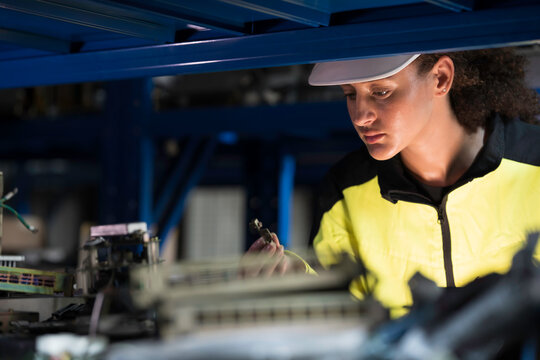 Woman worker using digital tablet working  and inspecting at shelves of electronic equipment parts in warehouse
