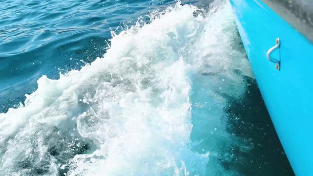 White boat wake splashing through deep blue sea