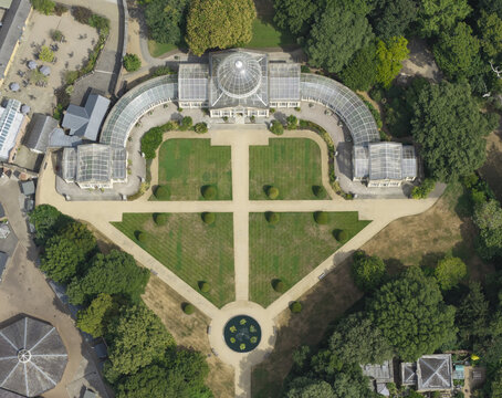 Aerial view of Syon House Great Conservatory surrounded by manicured lawns, gravel paths, and lush trees in London, Greater London, United Kingdom.