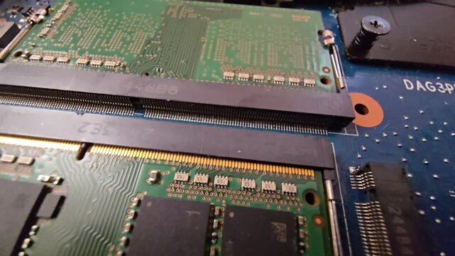 Macro close-up shot of a laptop motherboard, highlighting the RAM slots and memory module pins on the circuit board.