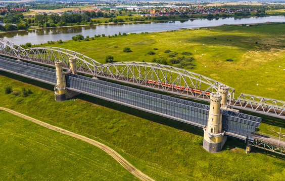 Aerial view of the historic Tczew Bridge with its stone towers and steel truss structure spanning the Vistula river surrounded by green meadows in Tczew, Pomeranian Voivodeship, Poland.