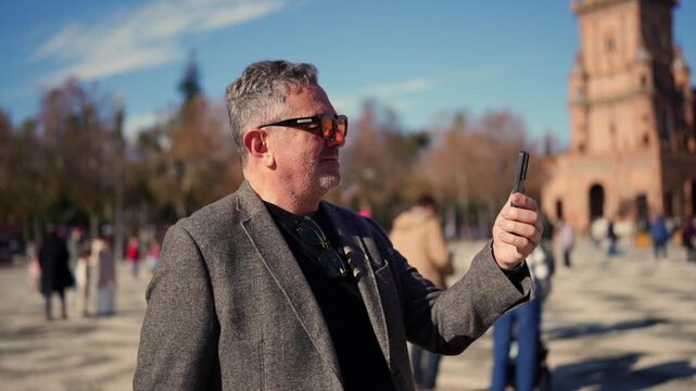 Mature tourist man video calling in plaza de espa&ntilde;a, seville