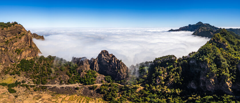 Aerial view of Cova Crater Panoramic Viewpoint with rugged volcanic peaks, lush vegetation, and a sea of clouds filling the crater basin in Faja de Cima, Porto Novo, Cabo Verde.
