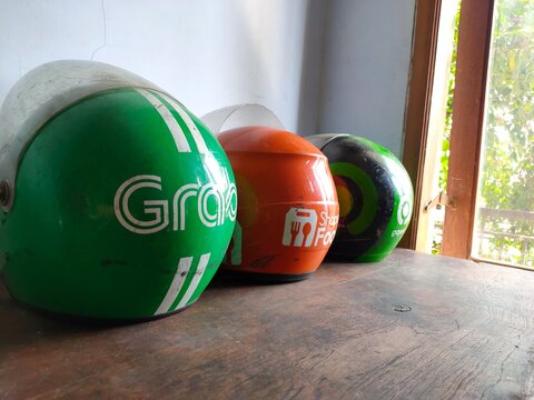 Malang, Indonesia - July 11, 2026: Three helmets used by Indonesian ride-hailing and delivery services: Grab, ShopeeFood, and Gojek. Helmet for rider. Gig worker. Freelancer. Freelance.