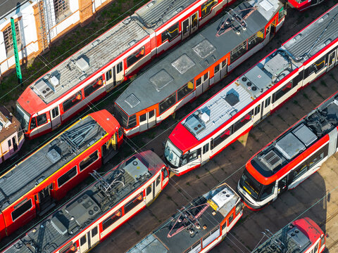 Aerial view of several red and white trams parked in the Nowy Port depot with parallel tracks and industrial surroundings in Gdansk, Pomeranian Voivodeship, Poland.