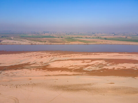 Aerial view of the Ravi river Siphon Lahore flowing through the landscape with sandy banks and agricultural fields in Ferozewala, Punjab, Pakistan.