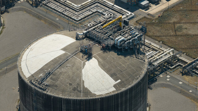 Aerial view of Dunkirk LNG Terminal showing large storage tank and complex industrial piping infrastructure in Loon-Plage, Hauts-de-France, France.