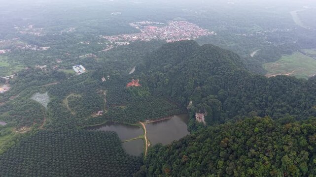 High-altitude drone view shows dense green forests and a calm lake at Kampar, Perak