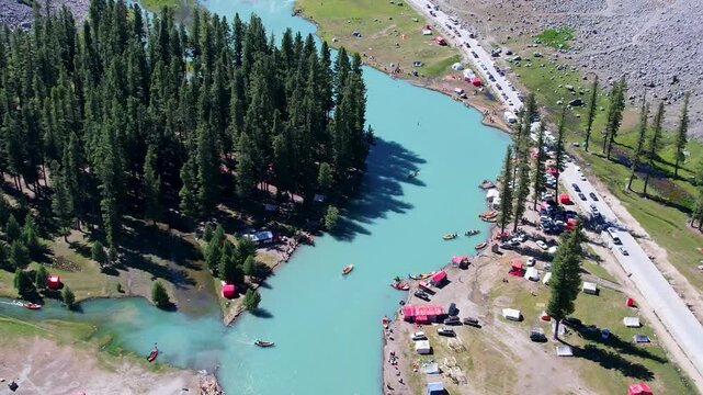 Boats move across Mahodand Lake beside cedar forest and campsites in Upper Ushu Valley, Khyber Pakhtunkhwa, Pakistan