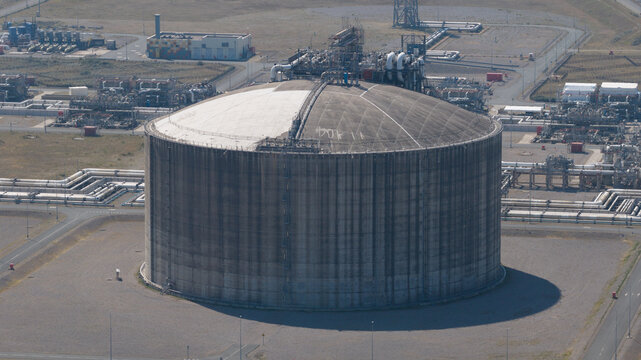 Aerial view of Dunkirk LNG Terminal featuring a large cylindrical storage tank surrounded by industrial infrastructure and pipelines in Loon-Plage, Hauts-de-France, France.