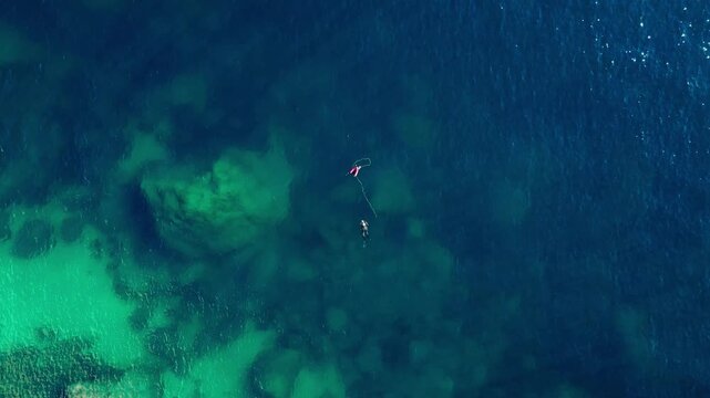 Aerial view of a diver swimming in the clear blue Mediterranean sea near the coast of Calp, Valencian Community, Spain.