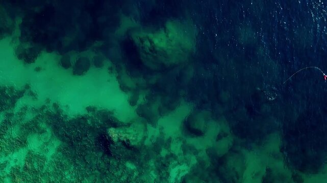 Aerial view of clear turquoise water and rocky seabed formations along the Mediterranean coast in Calp, Valencian Community, Spain.