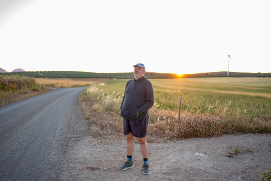 Man standing on rural road at golden hour sunset