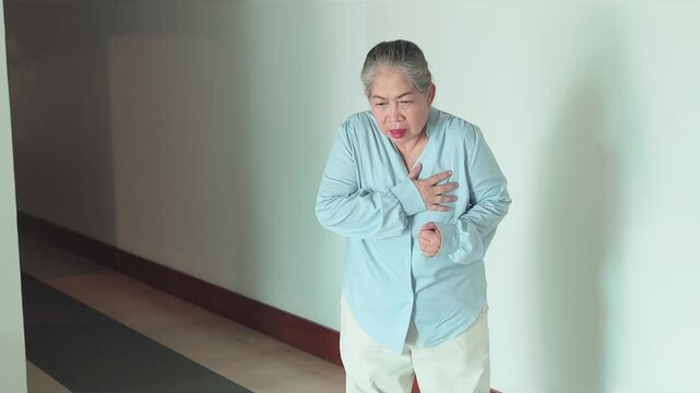 Panting and sick old aged elderly Asian woman suffering from heart condition, heart attack, irregular heartbeat, acid reflux