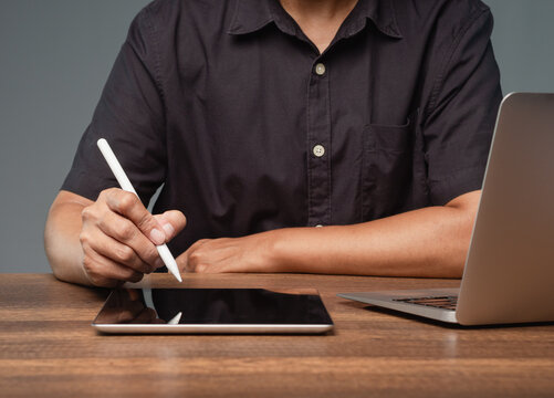 Person using tablet mockup with stylus beside laptop