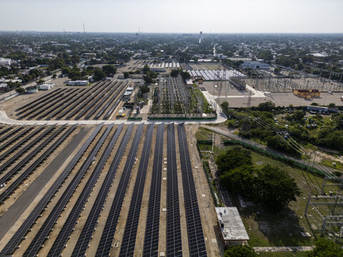 Aerial view of a solar power plant with rows of photovoltaic panels and electrical infrastructure situated within the urban landscape of Merida, Yucatan, Mexico.