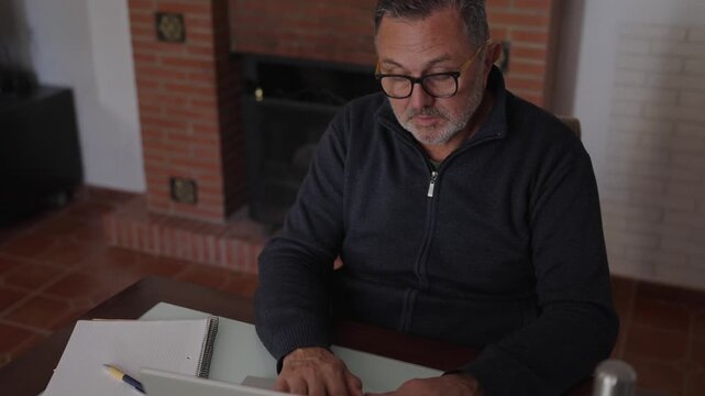 Mature businessman with glasses working remotely on laptop