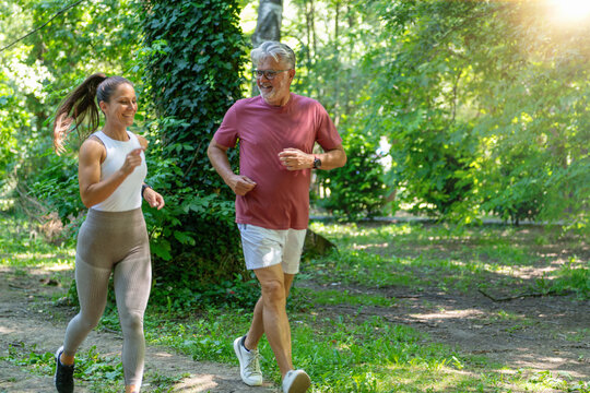 Senior man performing an endurance running exercise alongside a fitness coach to maintain cardiovascular health, improve mobility, and promote lifelong physical activity.