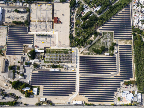 Aerial view of the solar and power plant featuring rows of photovoltaic panels and an electrical substation surrounded by urban infrastructure and greenery in Merida, Yucatan, Mexico.