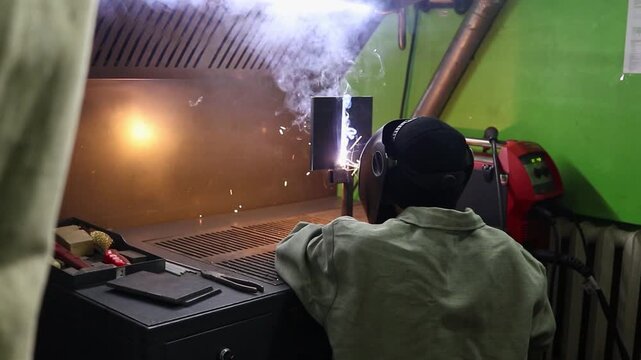 Student welds metal structure using MIG/MAG method in training workshop. Sparks, home and practical training of professions.