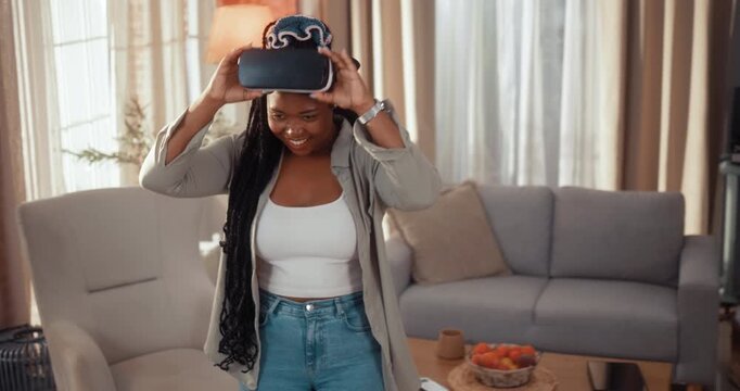 Happy young Black woman laughs with genuine joy after playing a virtual reality game in her living room at home.