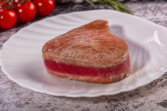 Gourmet seared ahi tuna steak with rare red center on white plate