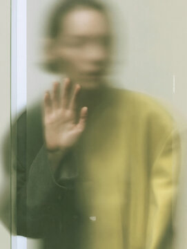 Blurred Woman Behind Frosted Glass with Raised Hand and Green Light