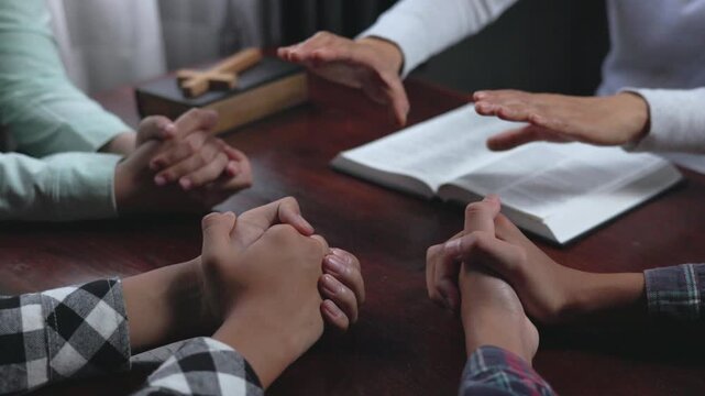 Christian group praying together in a quiet room around a wooden table, seeking God with faith, hope, peace, love, and spiritual unity.