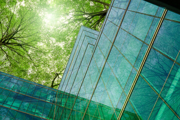 Eco-friendly building in modern city. Sustainable glass office building with trees for reducing carbon dioxide. Office building with green environment. Corporate building reduce CO2. Net zero emission © Fahroni