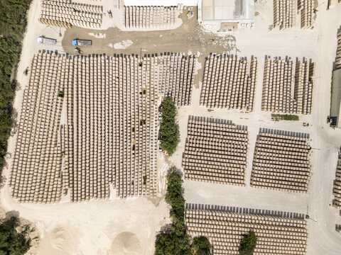 Aerial view of a brick factory with rows of stacked bricks, industrial storage area, and surrounding vegetation in Merida, Yucatan, Mexico.