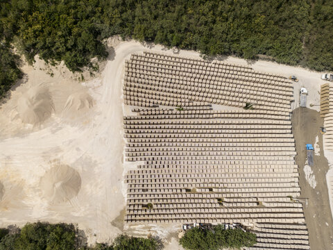 Aerial view of a brick factory with rows of stacked bricks, piles of raw materials, and surrounding greenery in Merida, Yucatan, Mexico.