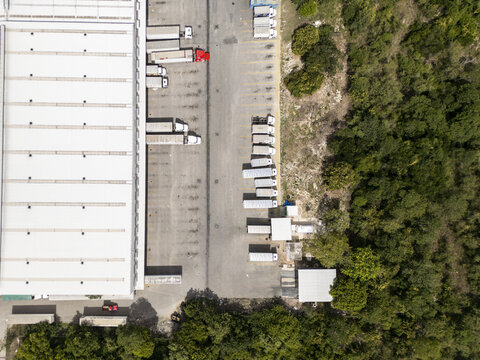Aerial view of the transportation logistics center with parked semi-trucks and trailers in the loading bays of a large warehouse facility in Merida, Yucatan, Mexico.