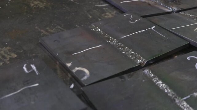 Weld samples on steel plates after work. Demonstration of welding quality and practical training results.