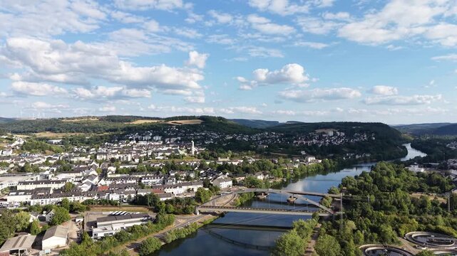 Drone aerial panorama of Konz, Germany, featuring the Saar River approaching its confluence with the Moselle, road bridges, residential neighborhoods, green hills and the surrounding river valley. Sce