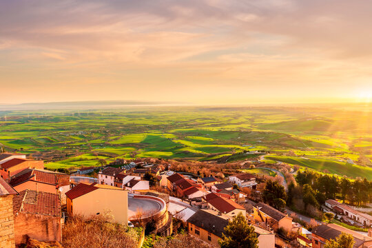 scenic evening sunset landscape with beautiful view og vintage town with traditional roofs and houses and green and golden walley hills with farmland and cloudy sky