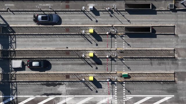 Top down aerial view of cars passing through a highway toll booth plaza